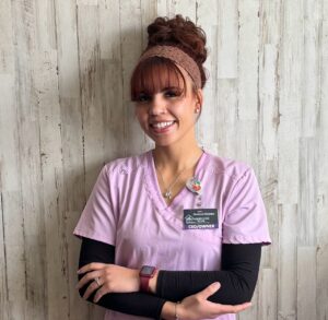 Smiling home healthcare owner in pink scrubs representing Homecare Plus in Albuquerque.