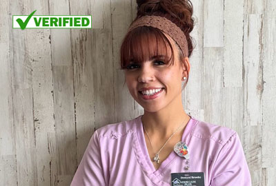 Smiling home healthcare owner in pink scrubs representing a local Albuquerque business.